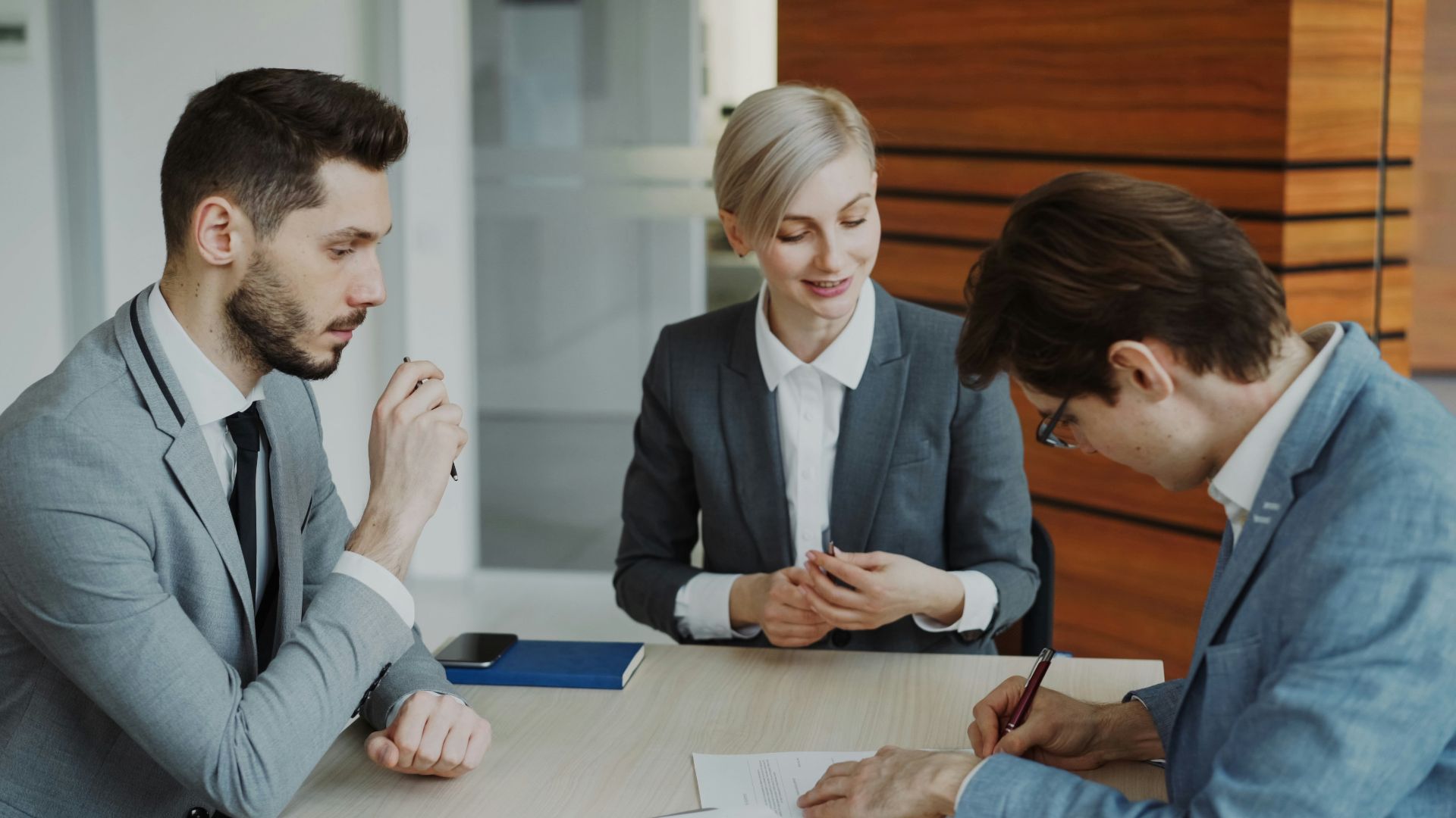 Business people signing a contract at a table.