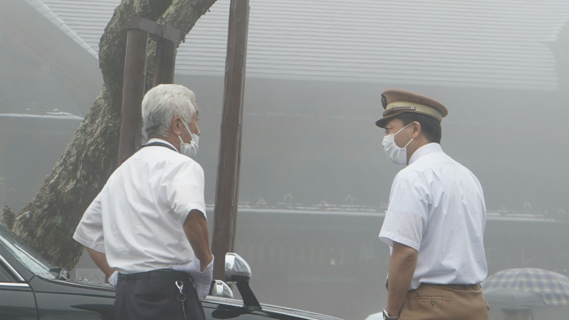A couple of men standing next to a black car