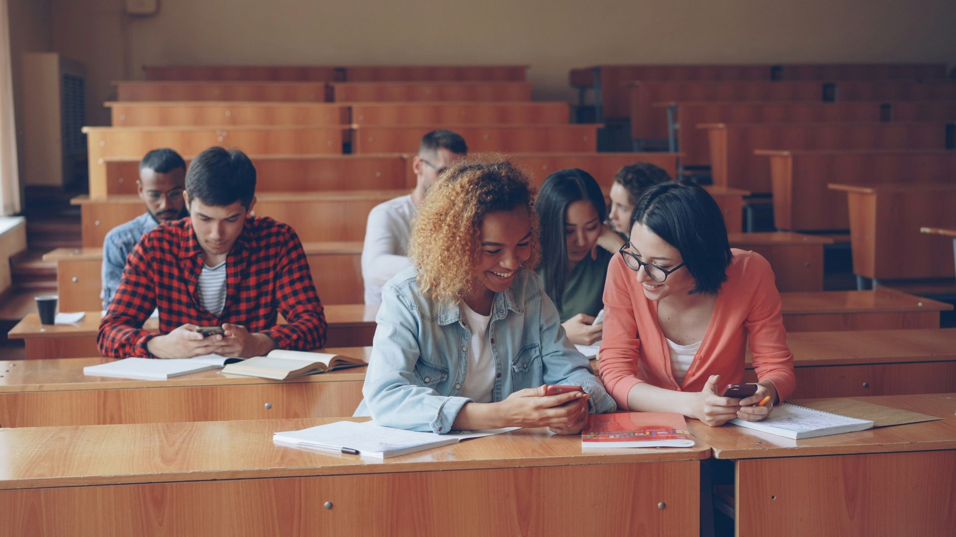 Students looking at phones in a lecture hall.