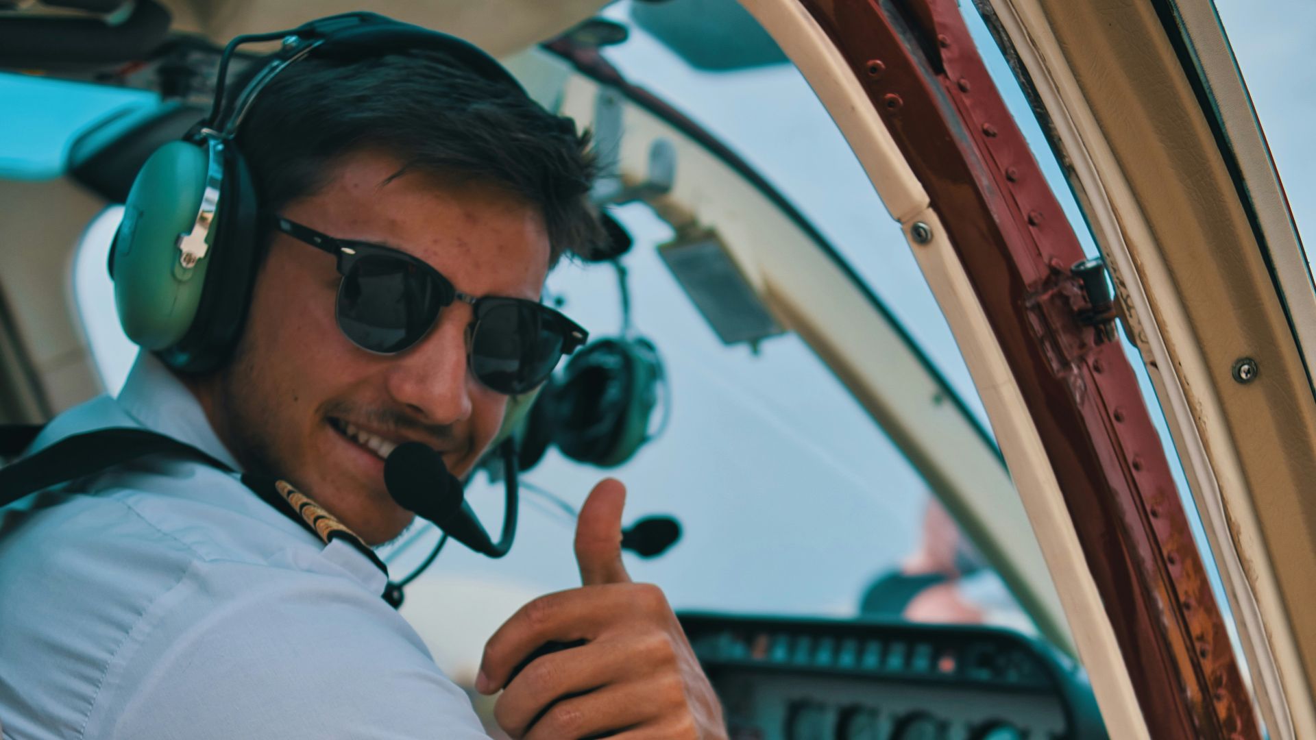 a man sitting in the cockpit of a plane giving a thumbs up