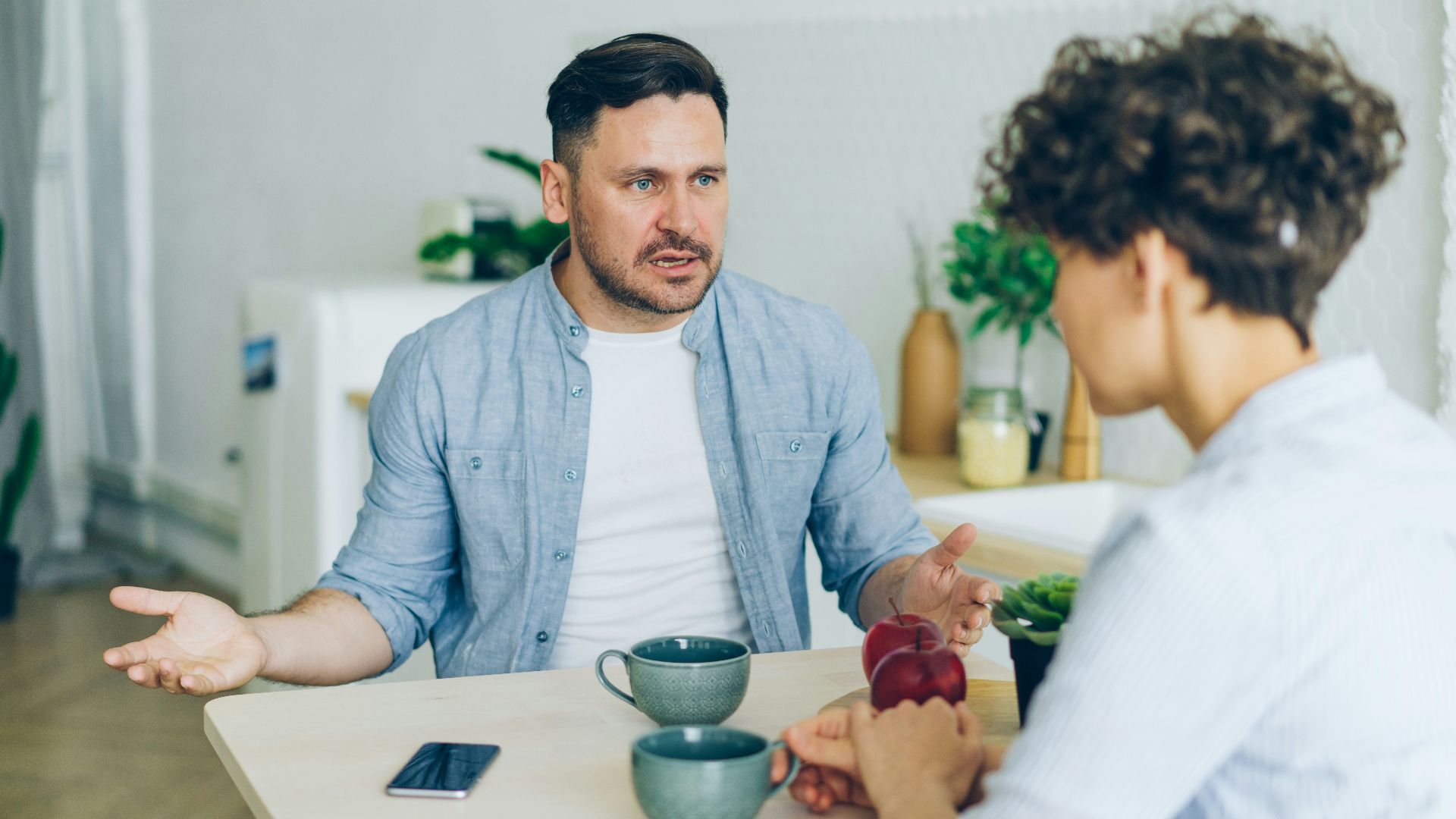 a man sitting at a table talking to a woman