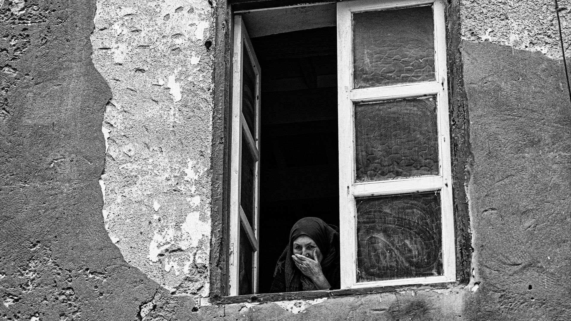 Woman looking out of a weathered window
