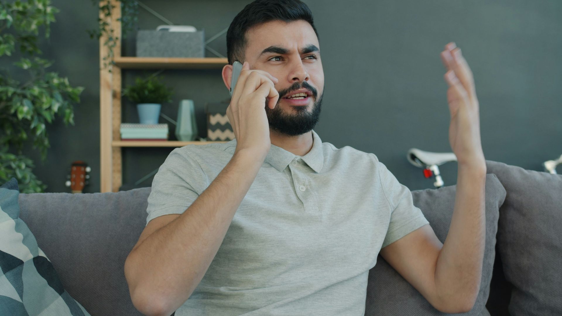 Man talking animatedly on the phone while sitting on couch.