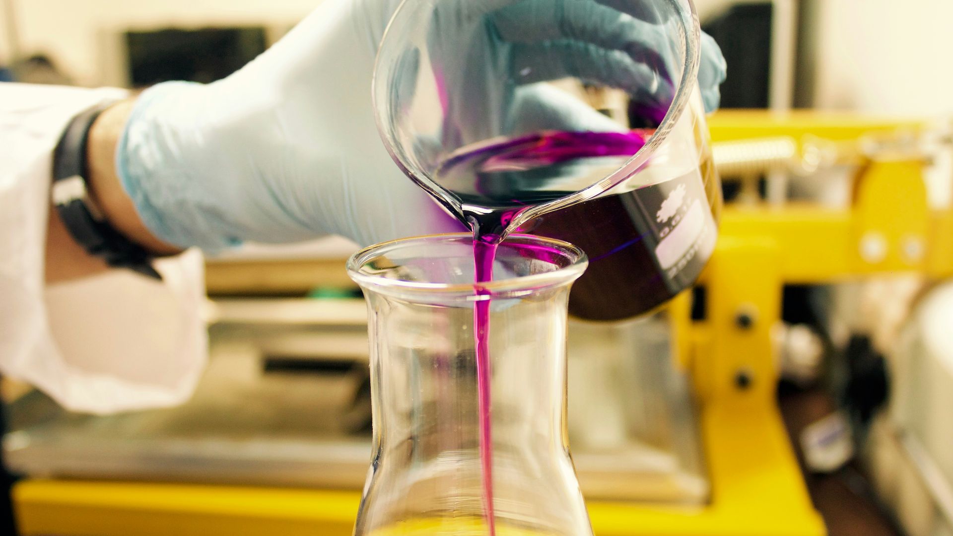 person pouring purple liquid on clear glass container