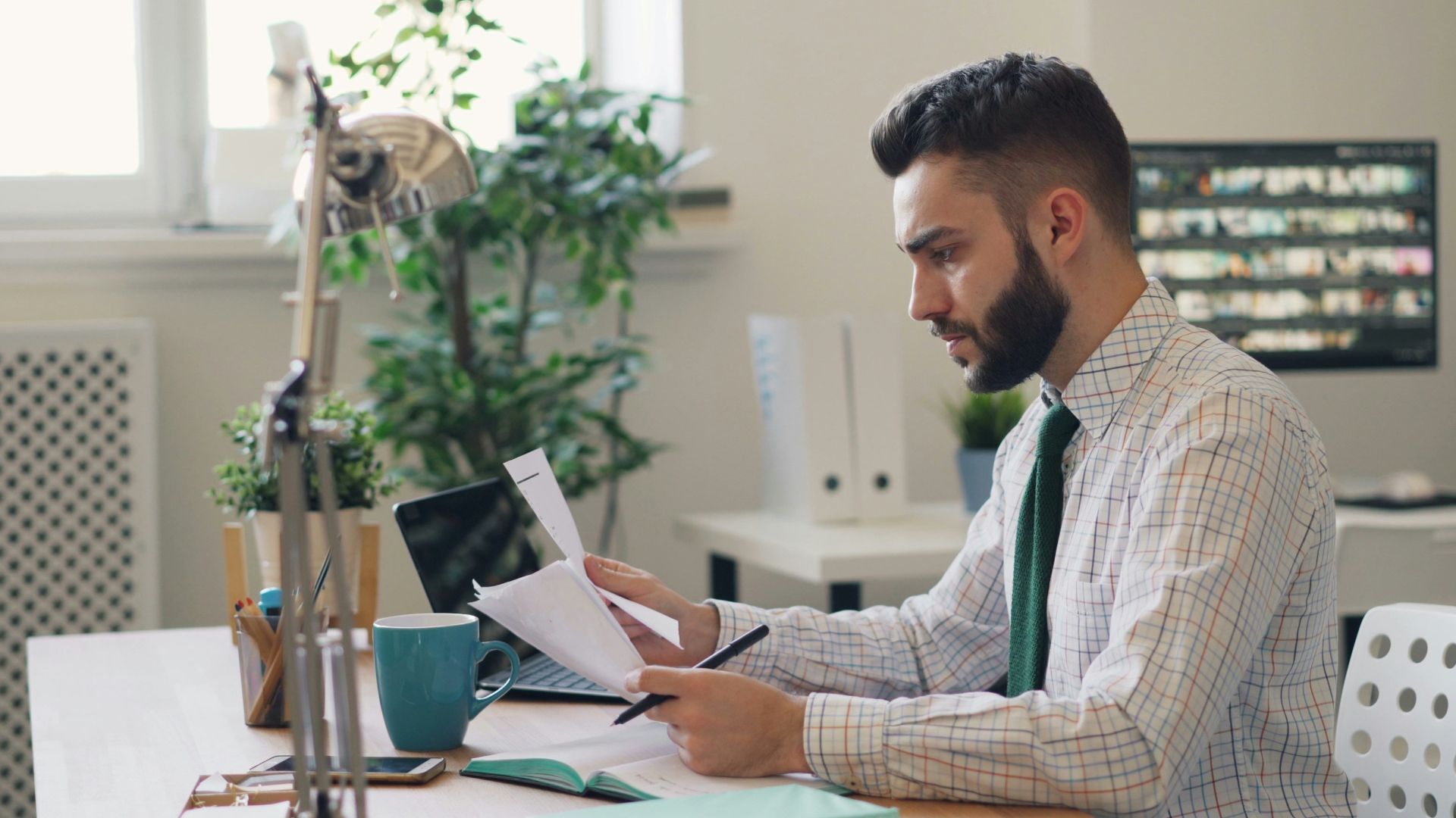 a man sitting at a desk with a laptop and papers