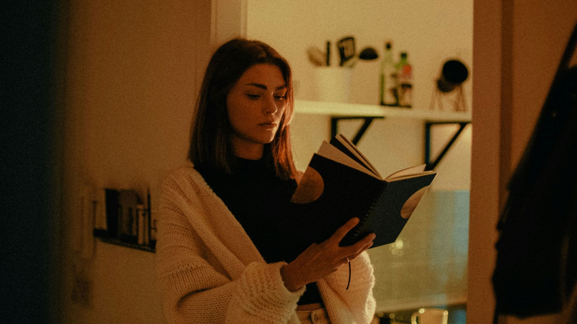 woman in white sweater holding book