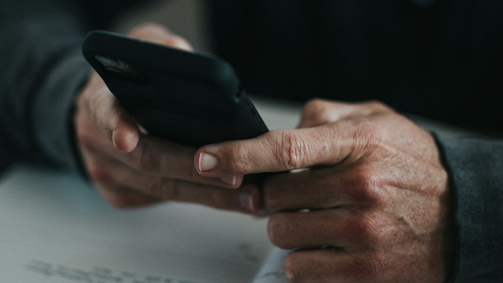person holding black smartphone on white paper