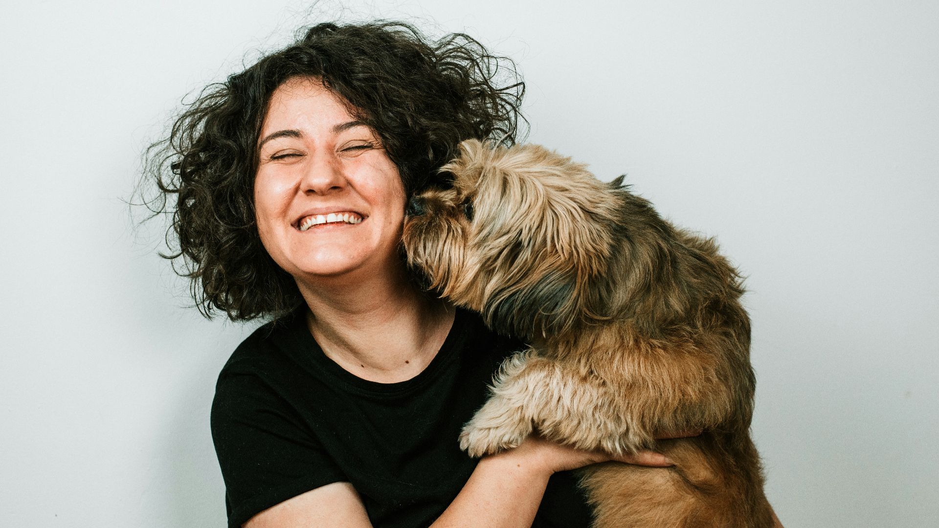 dog kissing woman in black crew-neck shirt