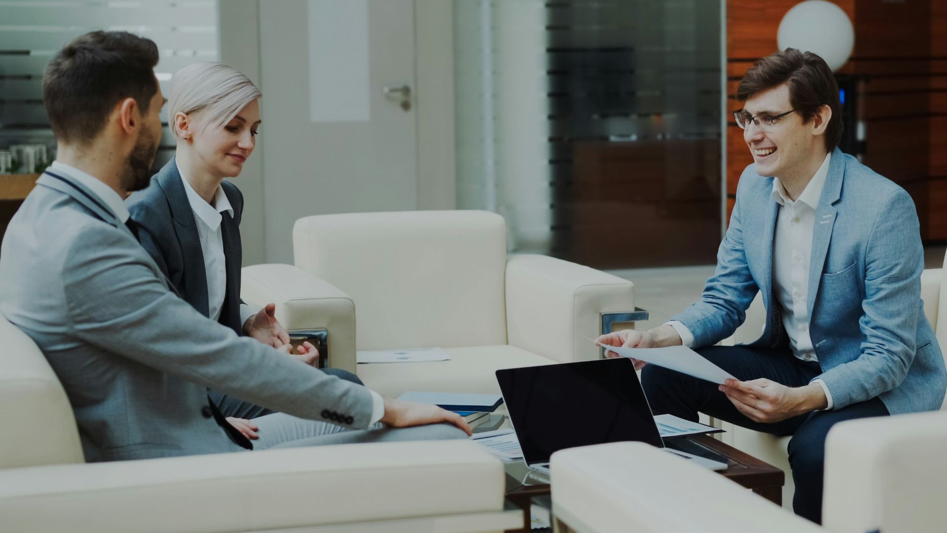 Three business people in a modern office meeting.