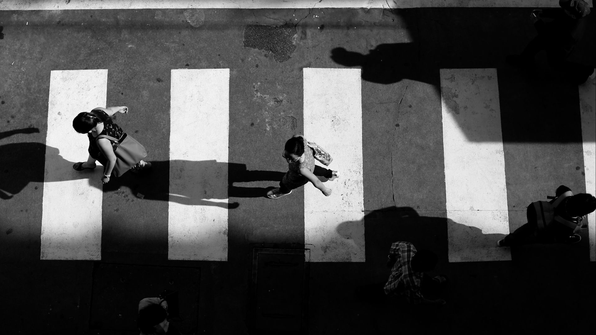 grayscale photo of people crossing pedestrian street