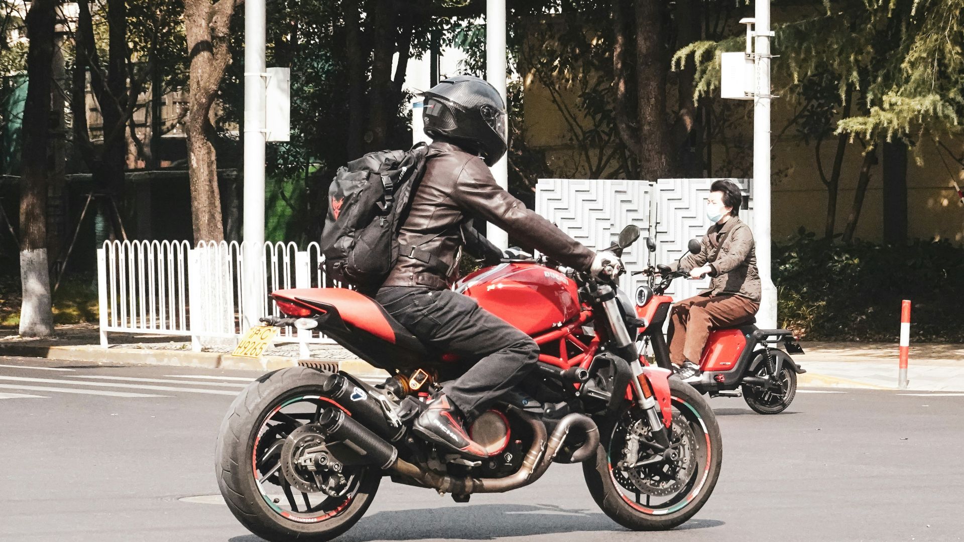 man in red jacket riding red motorcycle on road during daytime