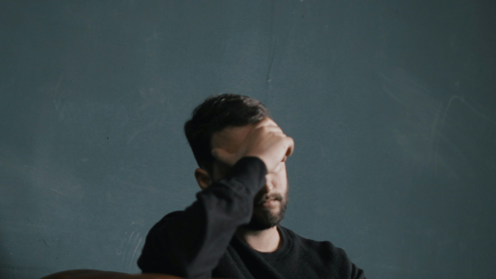 a man holds his head while sitting on a sofa