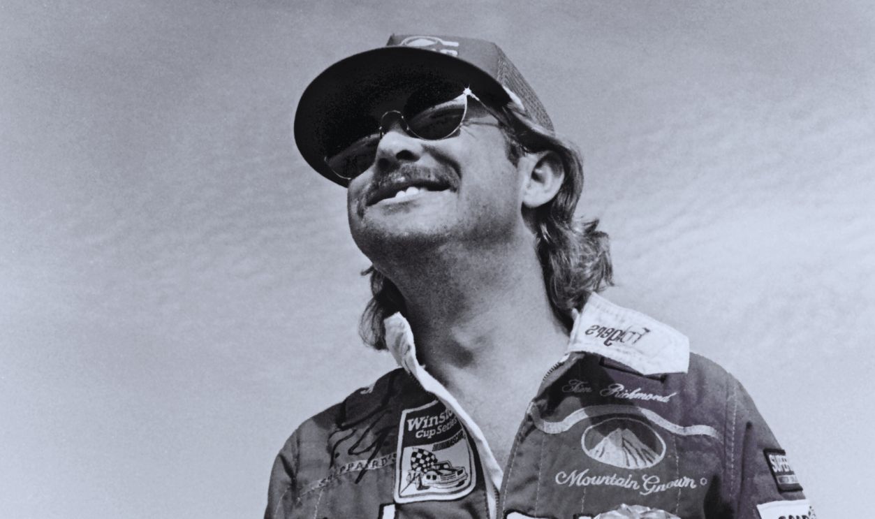 Gettyimages - 1288878942, NASCAR driver Tim Richmond DAYTONA BEACH, FLORIDA - JULY 1987: NASCAR driver Tim Richmond eats a sandwich as he stands beside his racecar prior to the start of the 1987 Pepsi Firecracker 400 stock car race at Daytona International Speedway in Daytona Beach, Florida. 