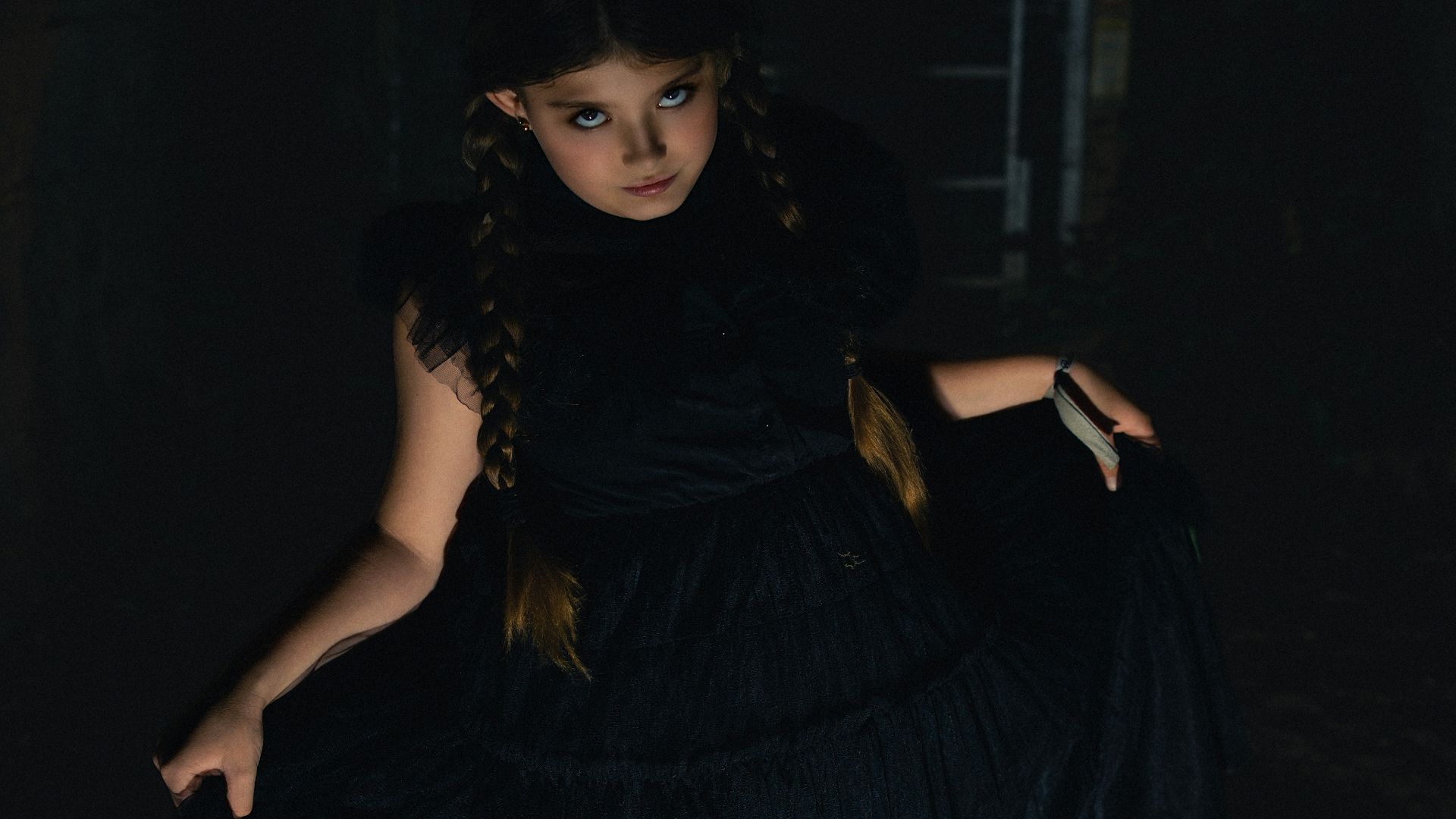 A young girl in a black dress with pigtails.