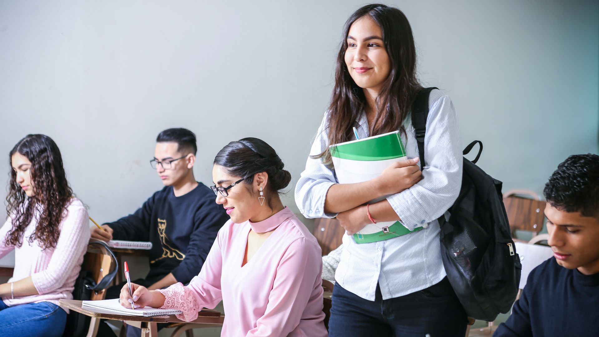 woman carrying white and green textbook