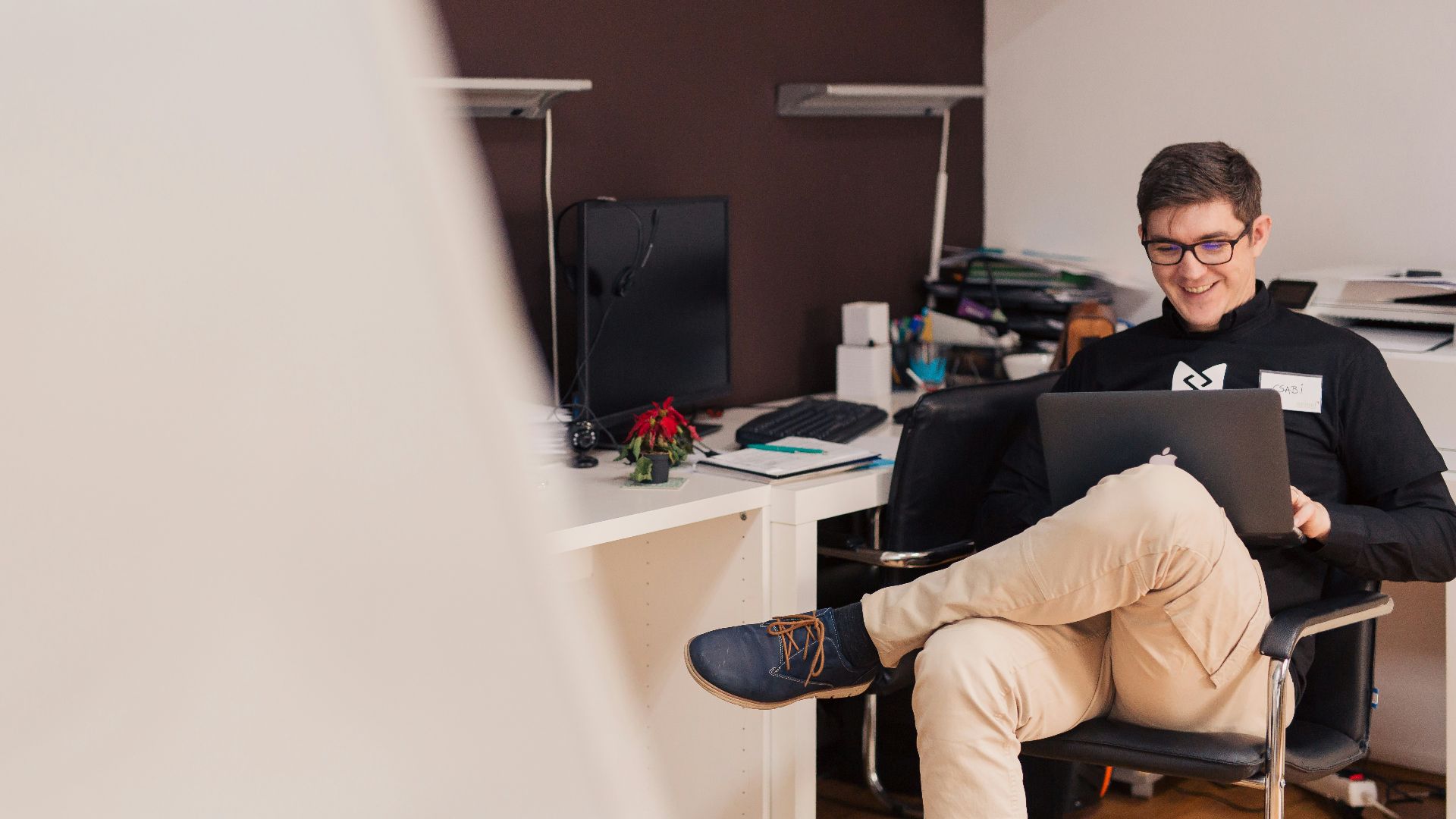 man smiling while sitting and using MacBook