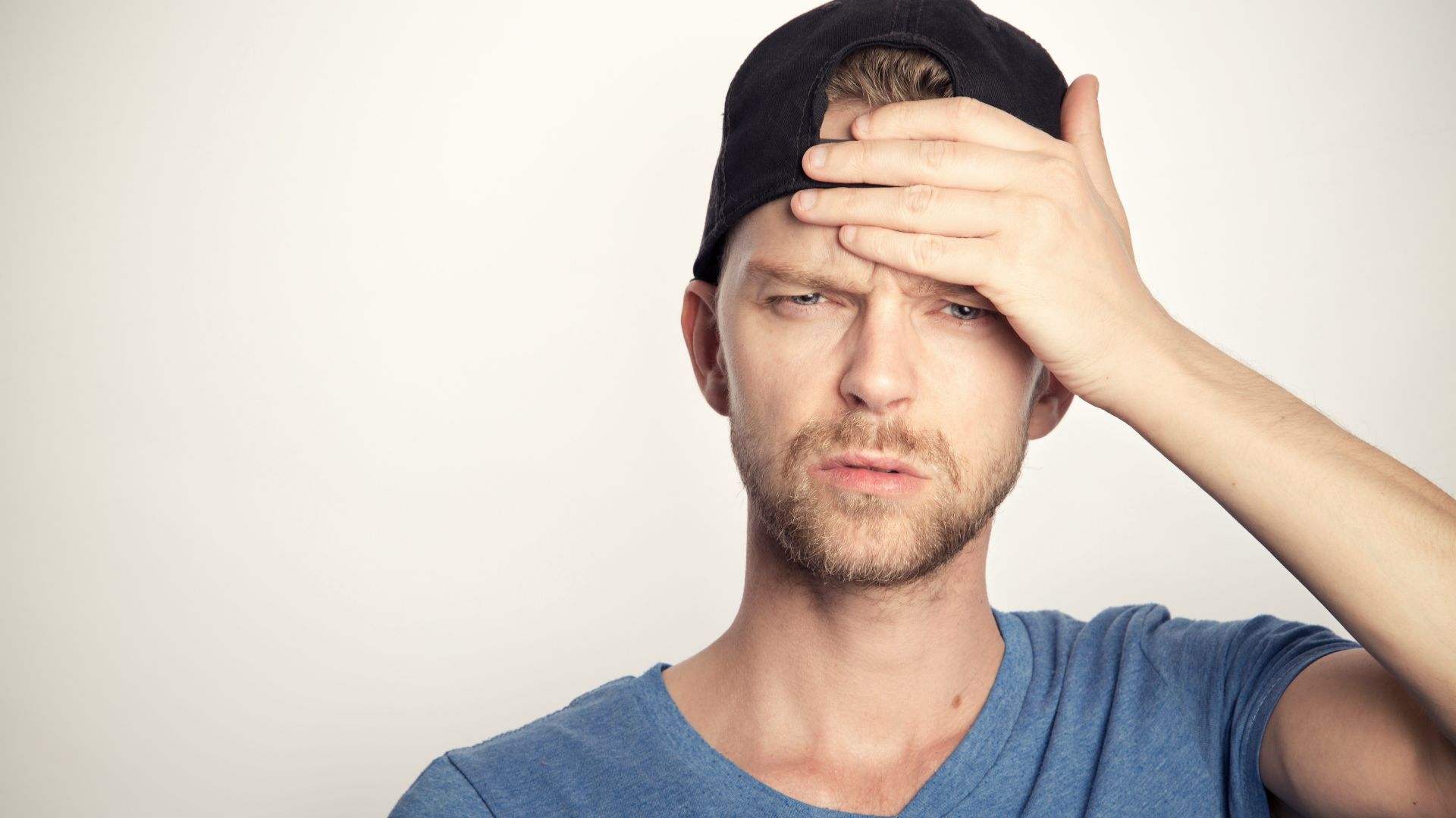 man in blue crew neck shirt covering his face