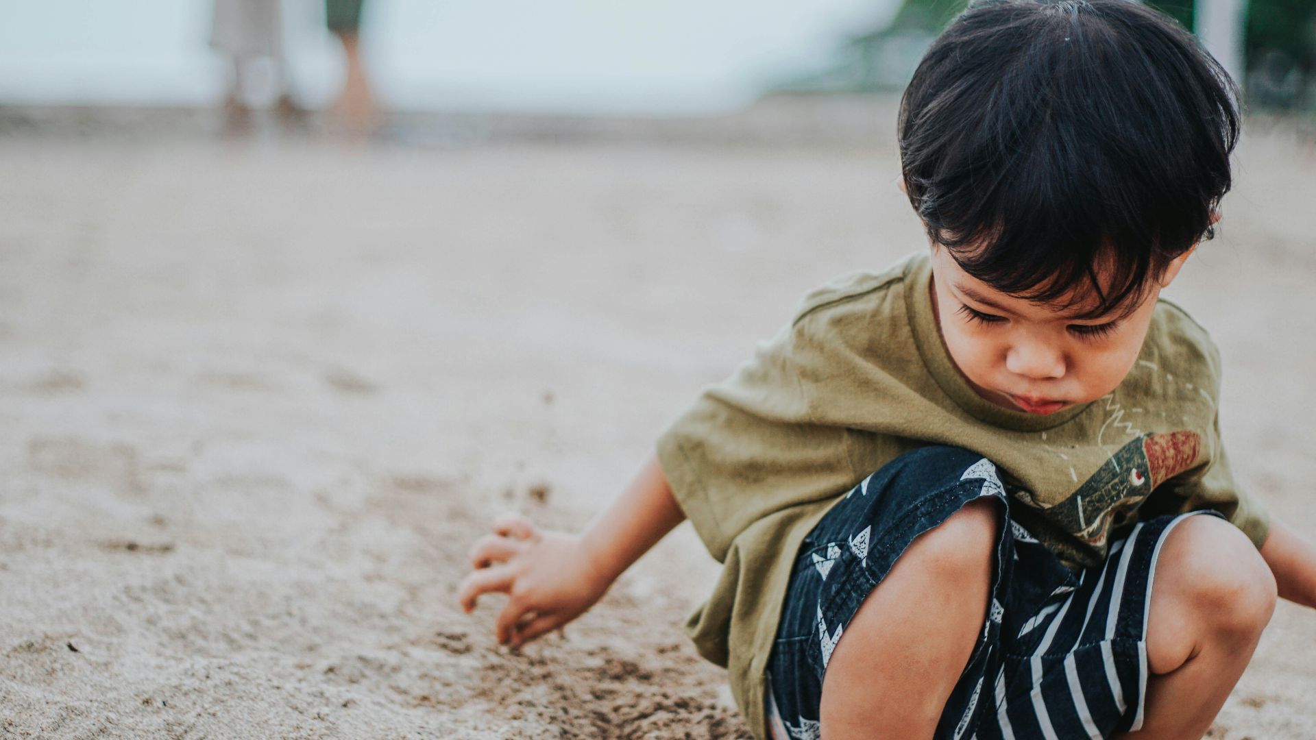boy in brown shirt lying on brown sand during daytime