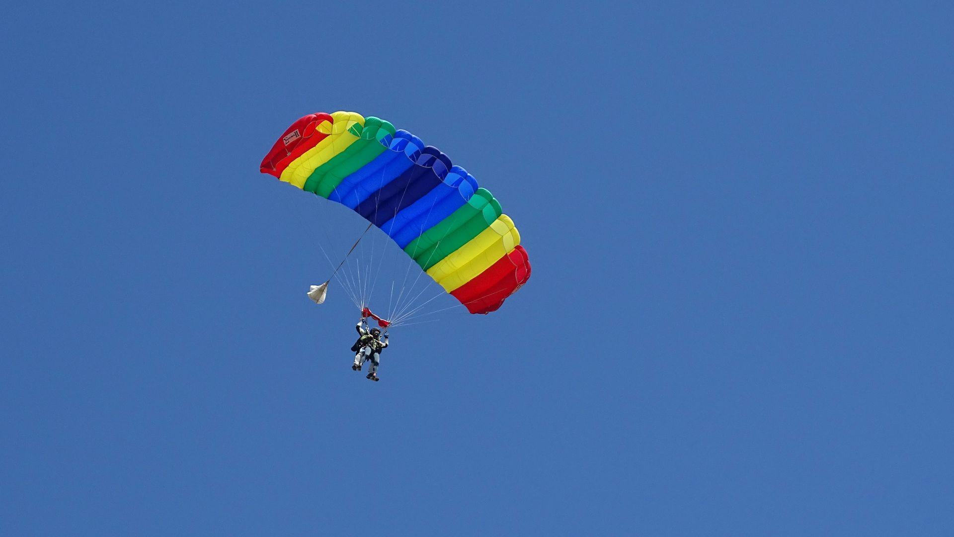 person riding on red yellow and blue parachute