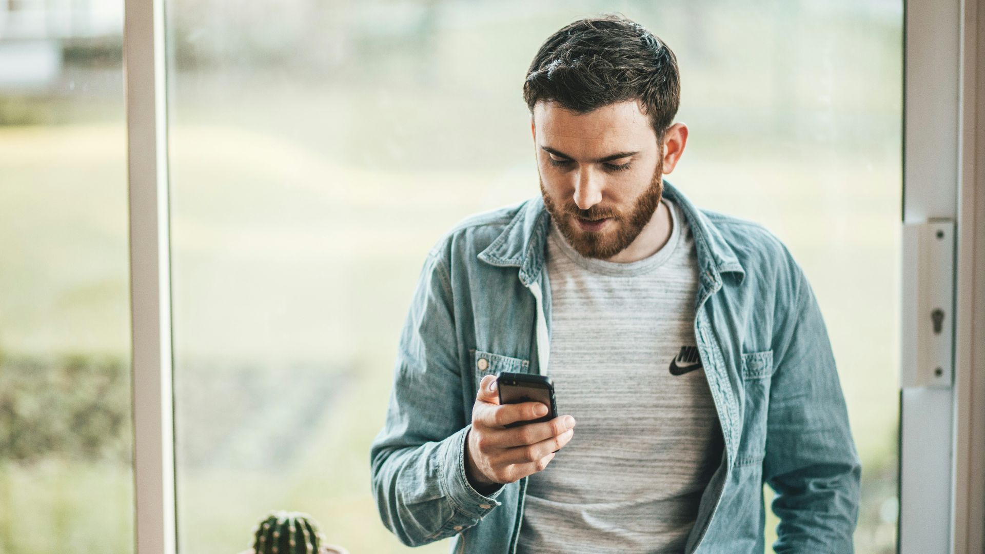 man holding a smartphone near the window