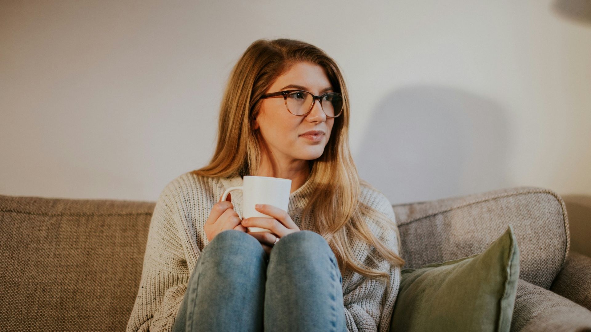 woman in blue denim jeans sitting on gray sofa