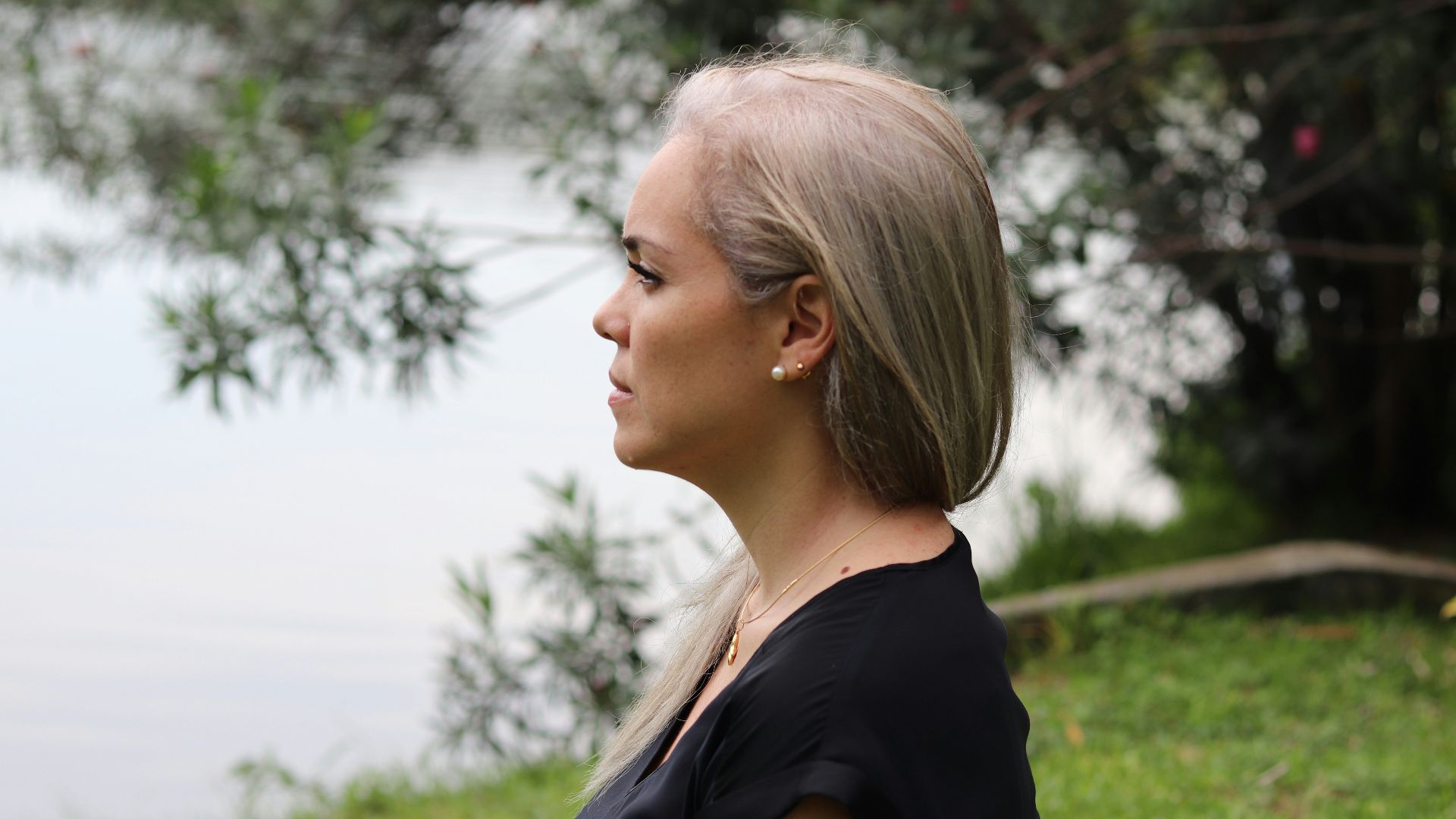a woman with blonde hair standing in front of a body of water
