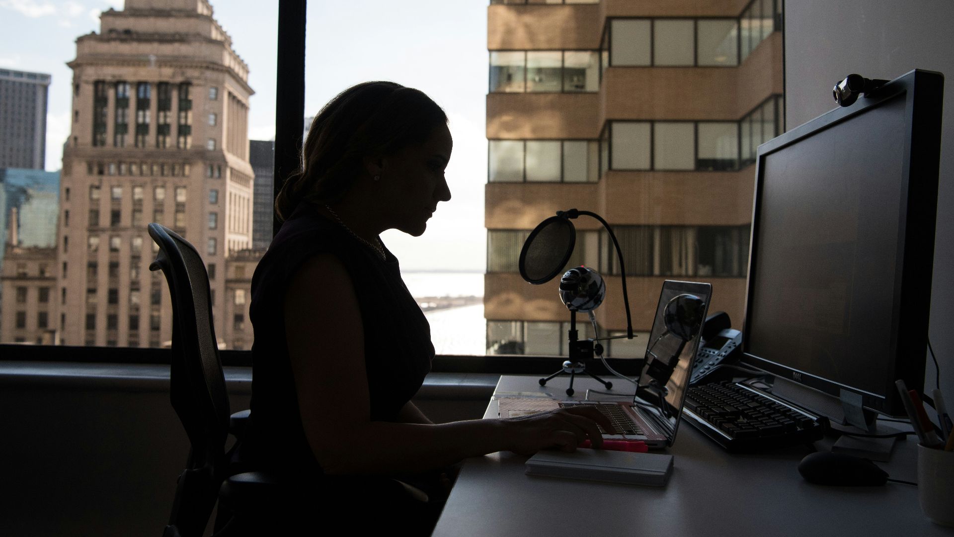 woman sitting in front of desk with computer monitor and keyboard on top