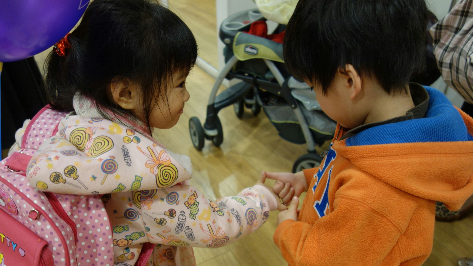 Two young children holding hands indoors.