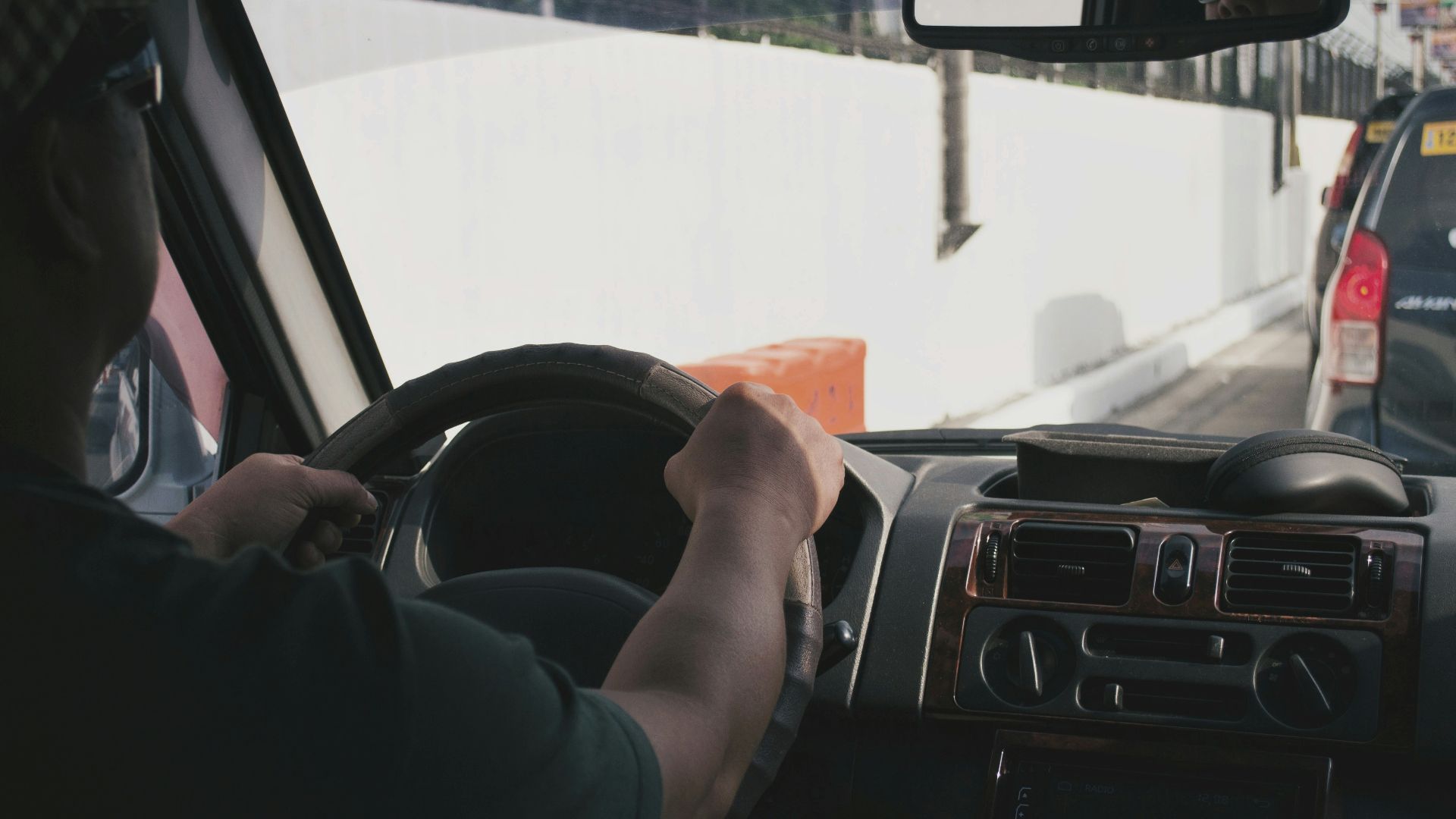 person driving vehicle on road near vehicle at daytime