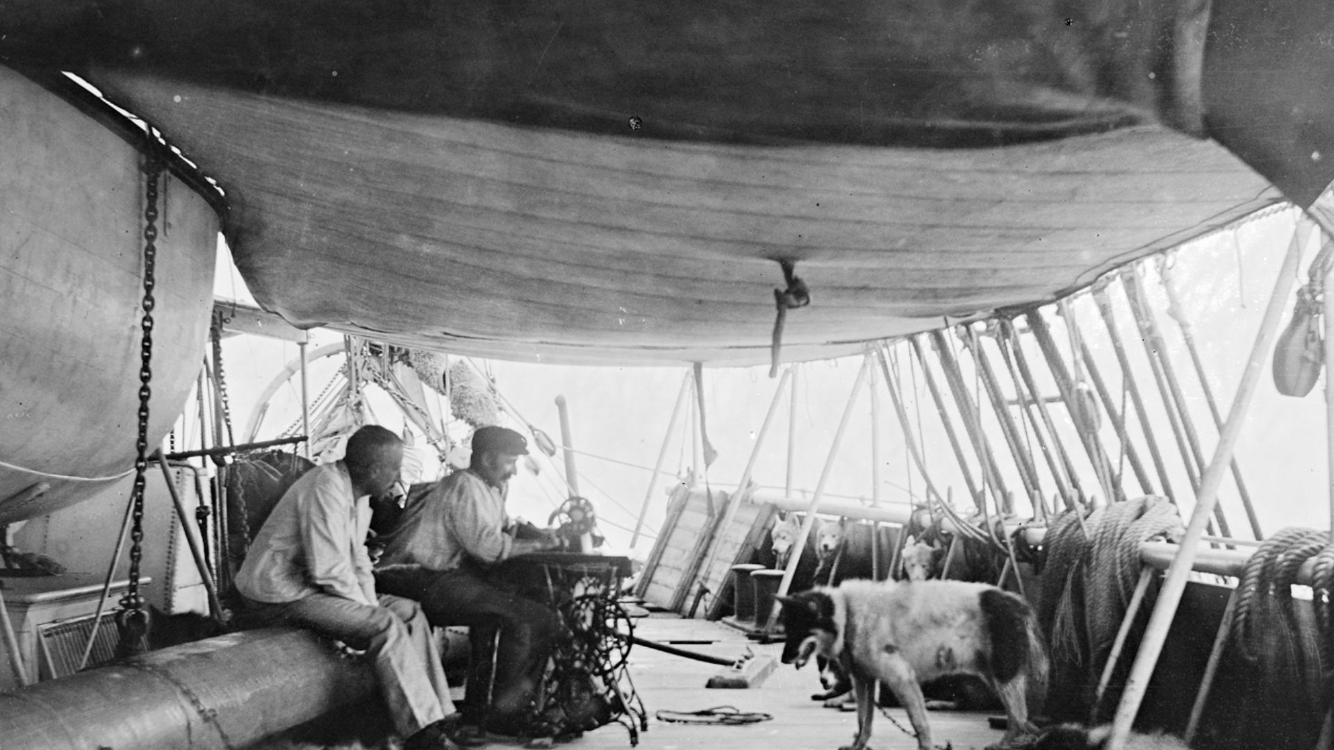 File:Roald Amundsen ser på Martin Rønne som syr på maskin, 1910 (7675744350).jpg