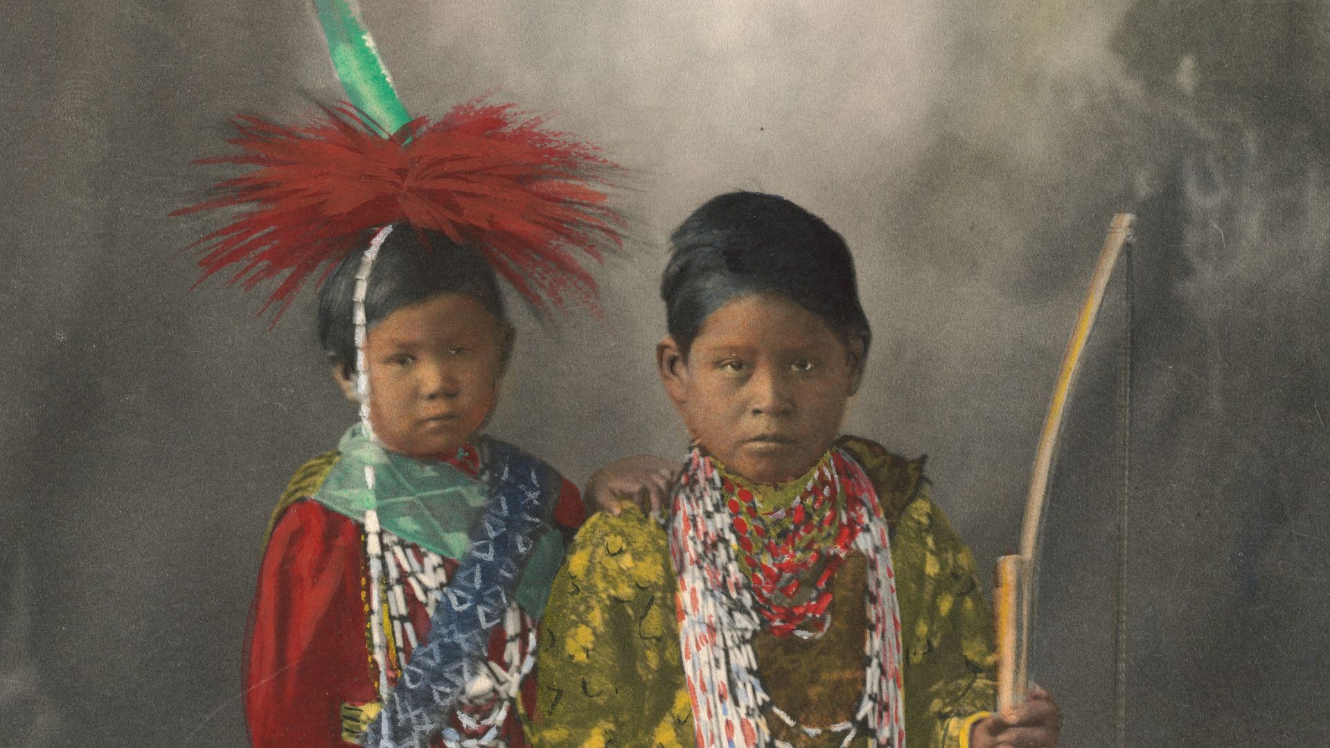 2 women in traditional dress holding stick