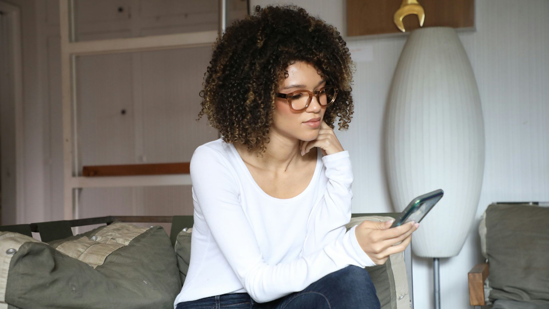 woman in white long sleeve shirt and blue denim jeans sitting on bed