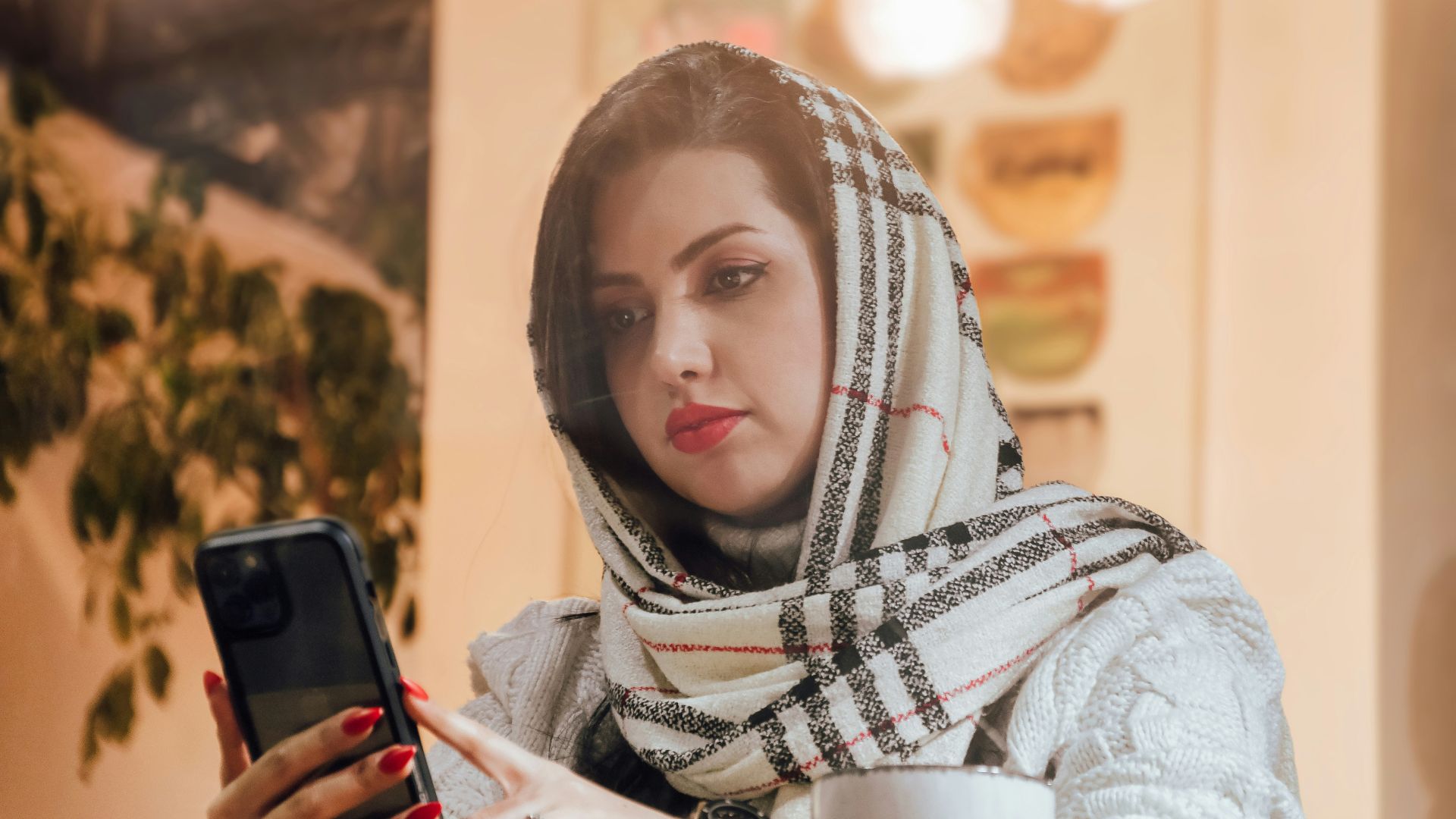 a woman in a scarf looking at a cell phone