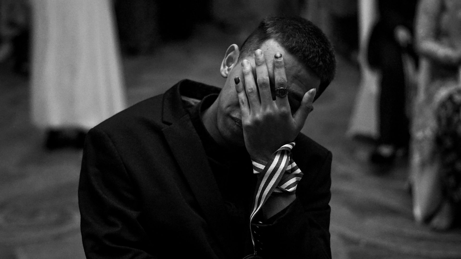 Man in suit covers face with hand