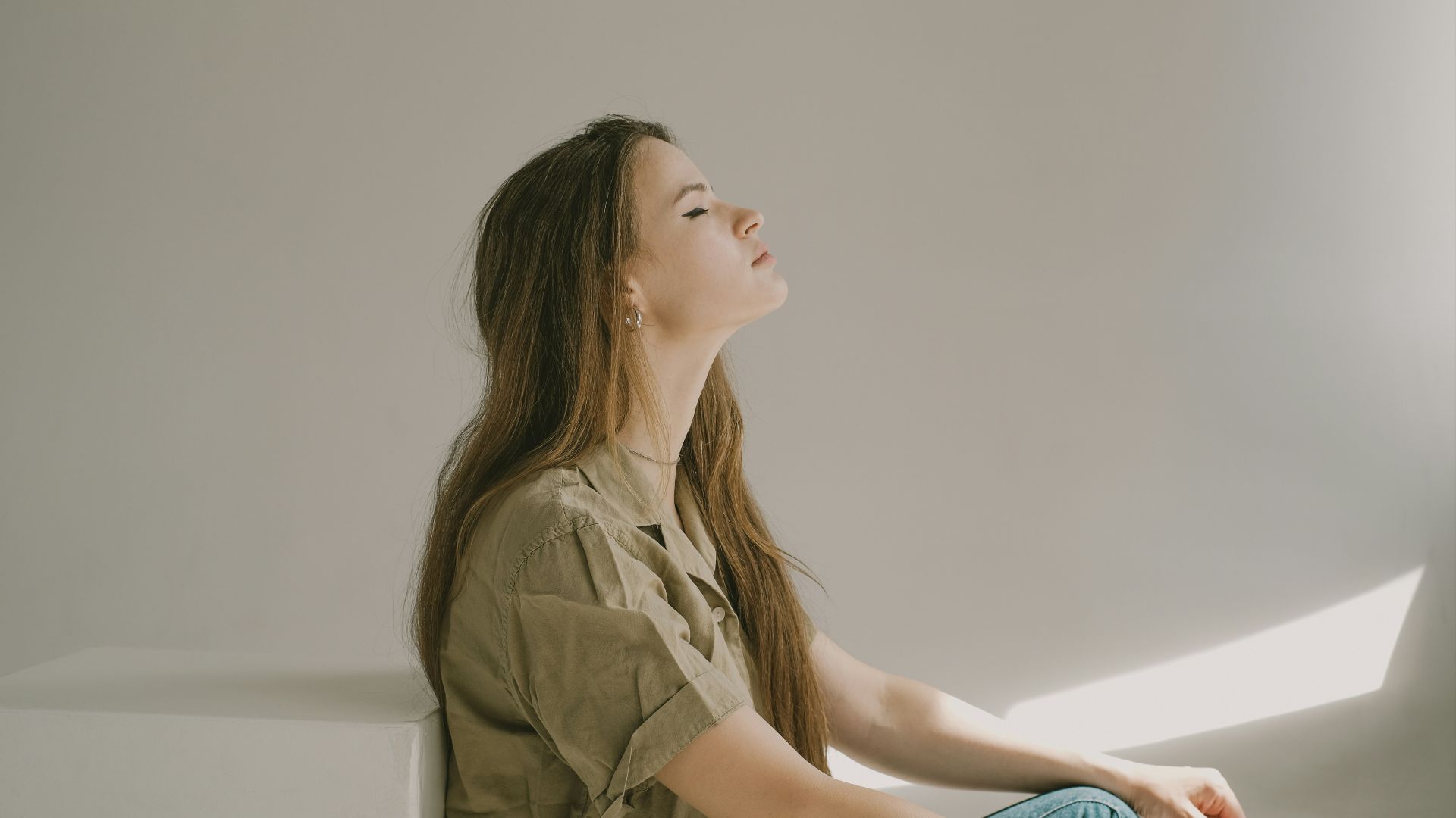 a woman sitting on a ledge looking up at the sky