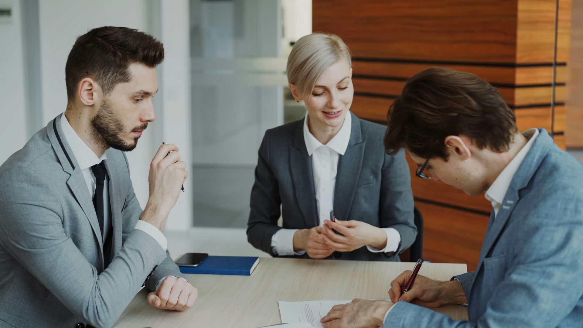 Business people signing a contract at a table.