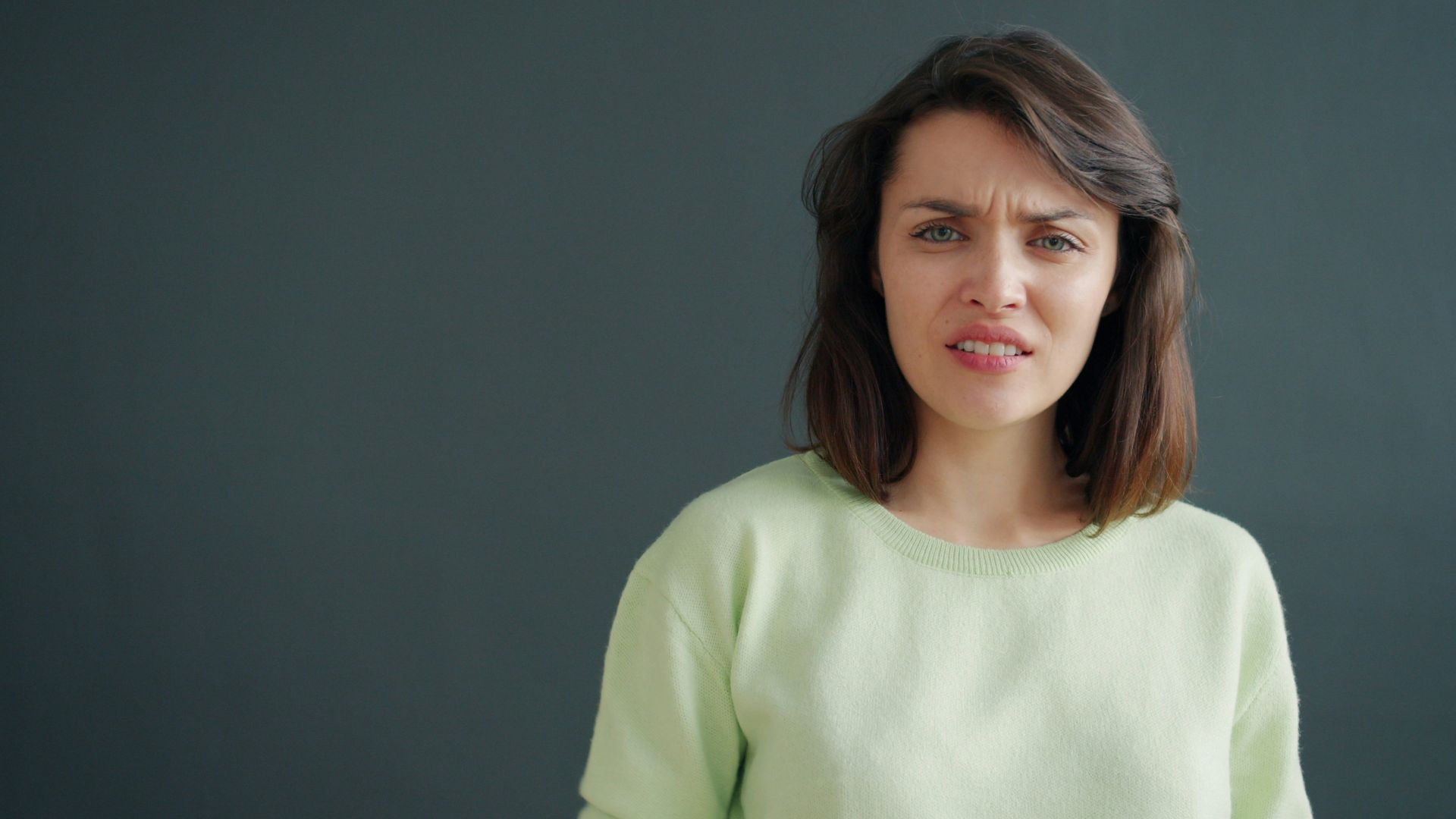 Woman with a disgusted expression against a dark background