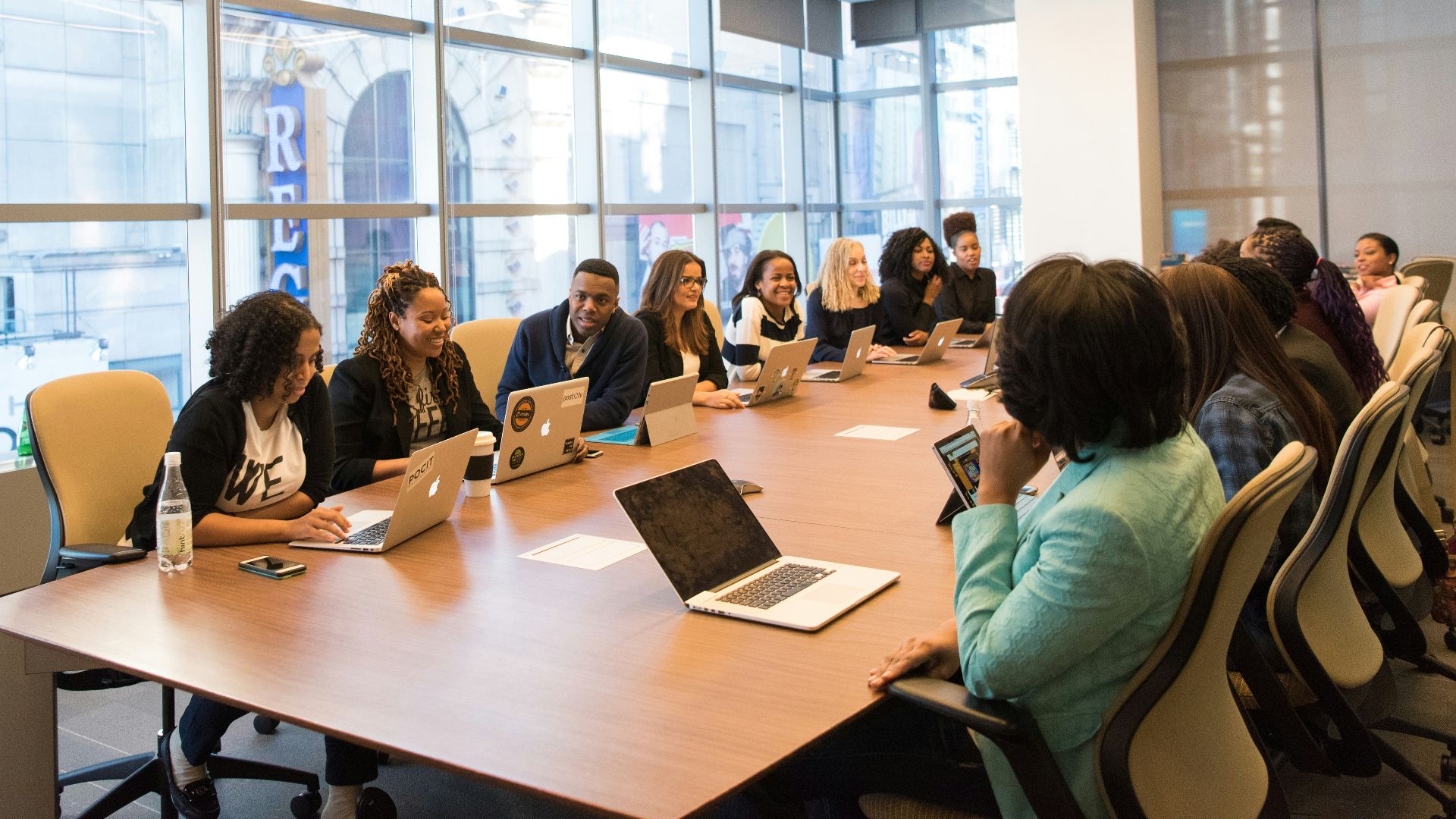 group of people sitting beside rectangular wooden table with laptops