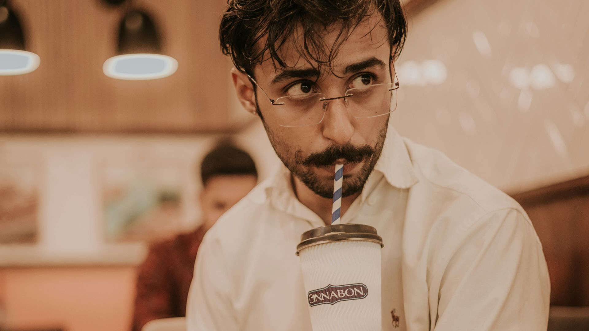 man in white polo shirt holding white ceramic mug