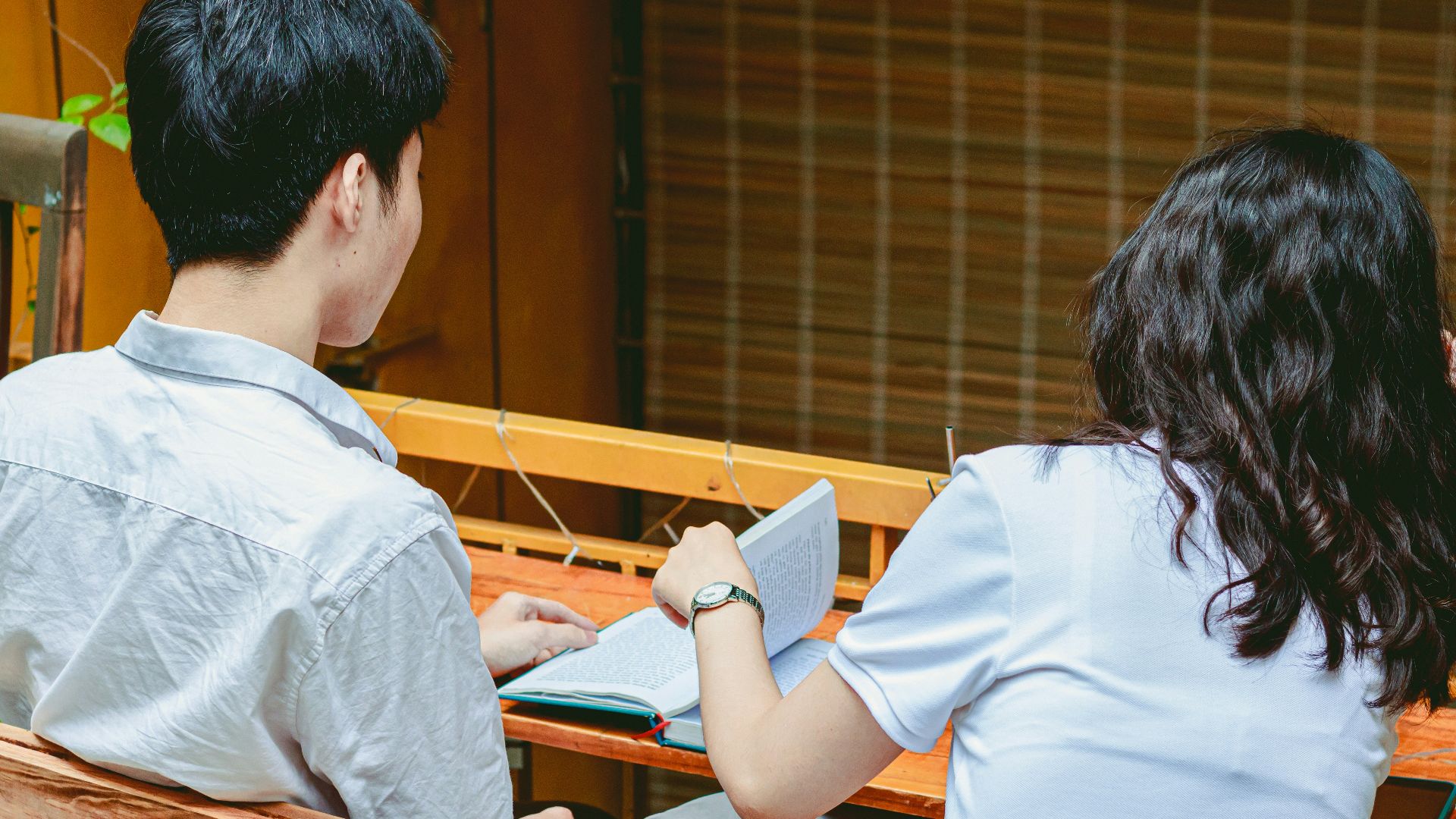 a man and a woman sitting at a table looking at a book