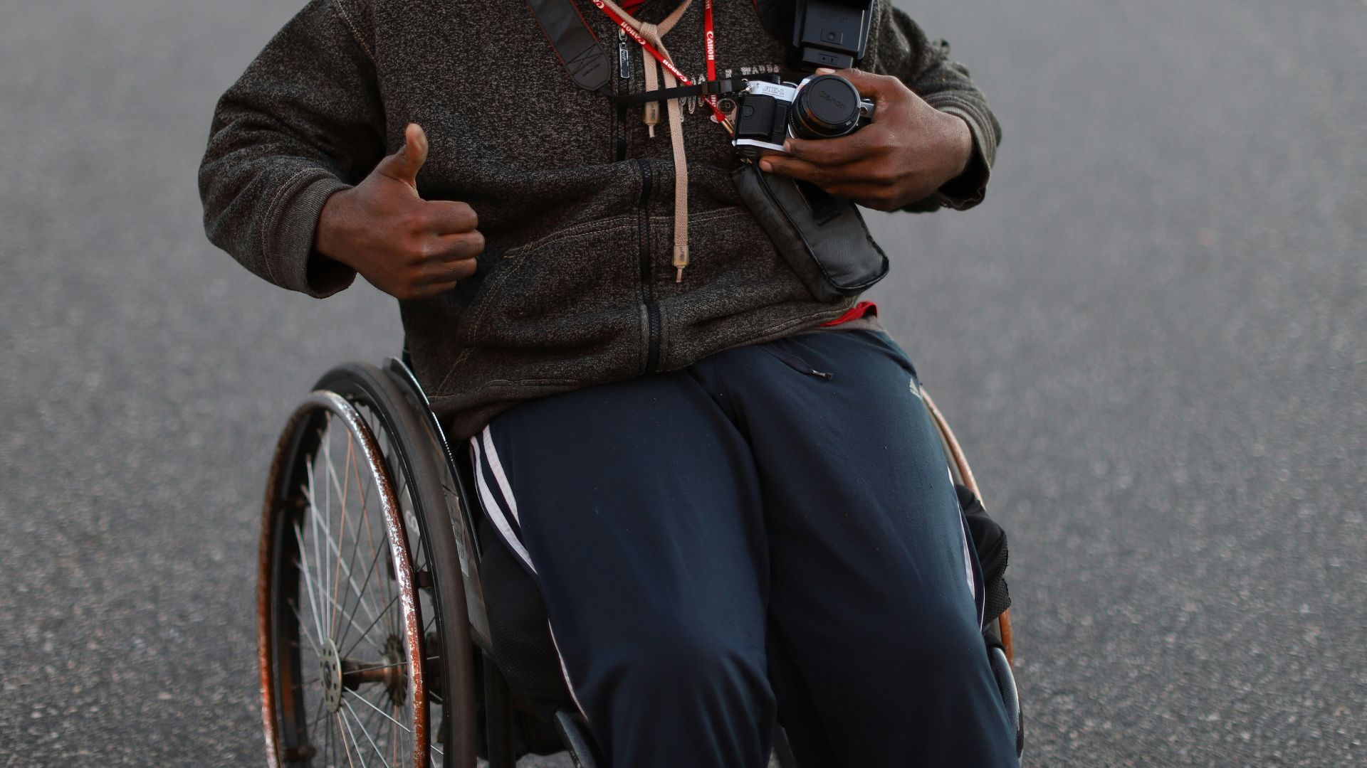 a man in a wheelchair pointing a camera