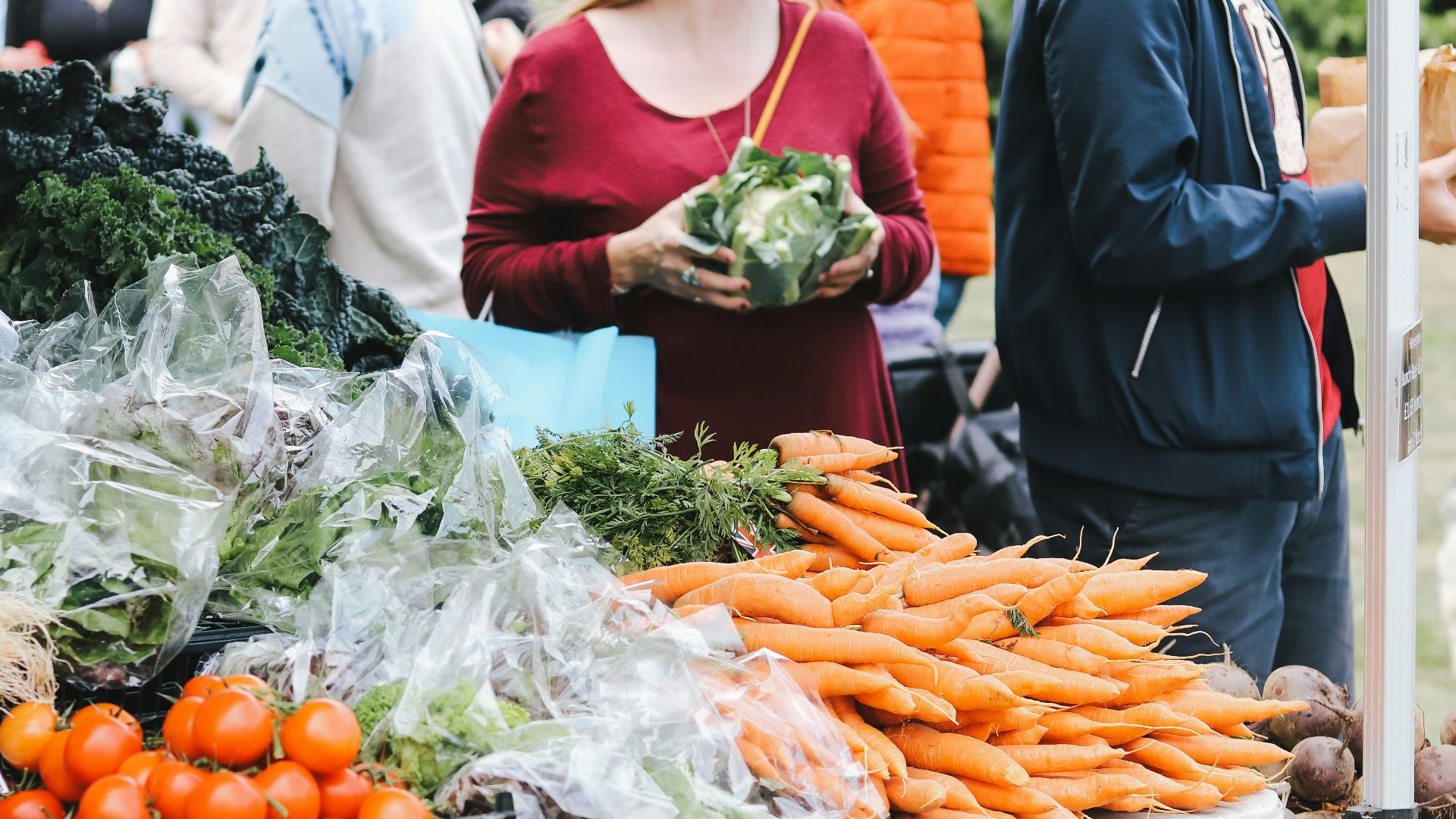 a group of people standing around a table filled with vegetables