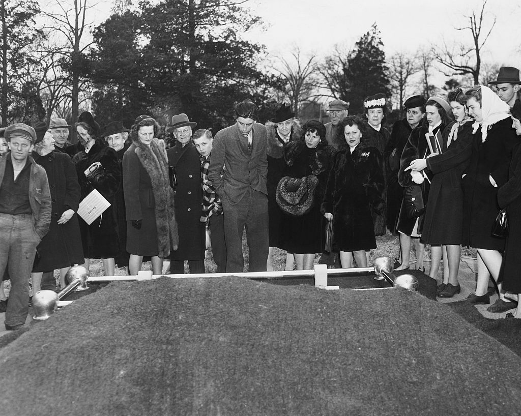 A handful of cousins and some curious spectators view the grave of Homer Collyer