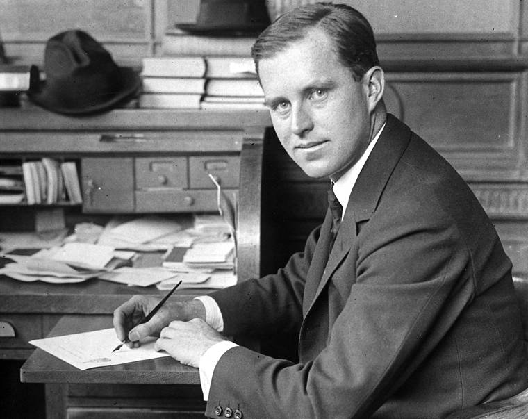 Joseph P. Kennedy at a desk in suit, working