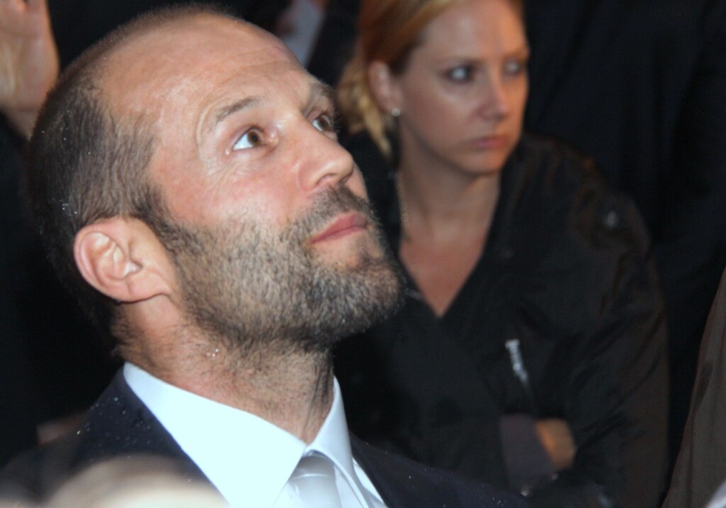 Jason Statham wearing a suit and looking up