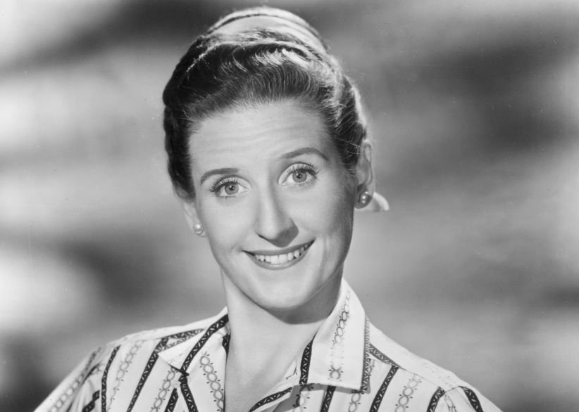Studio portrait of American actor Ann B Davis wearing striped blouse and smiling