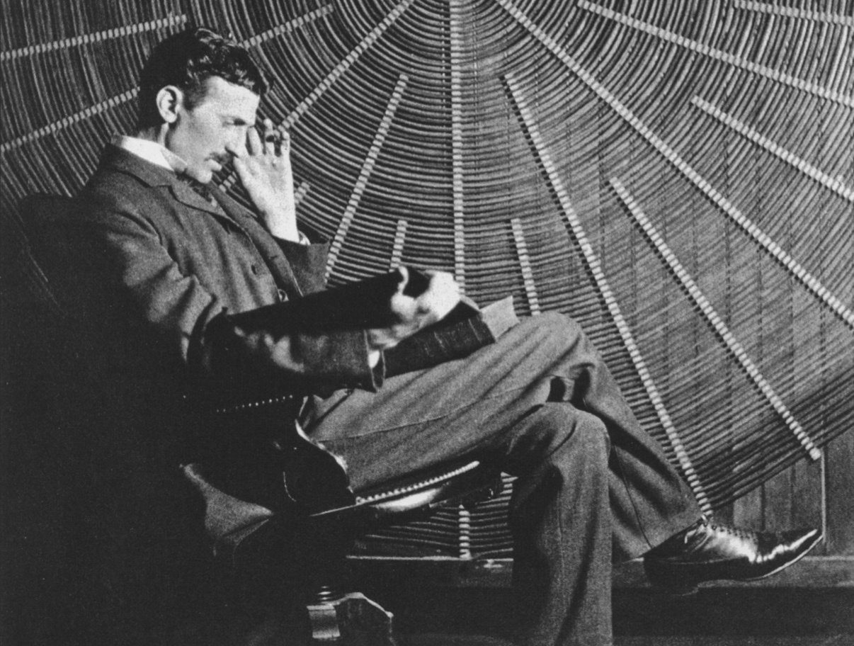 Tesla sitting in front of a spiral coil