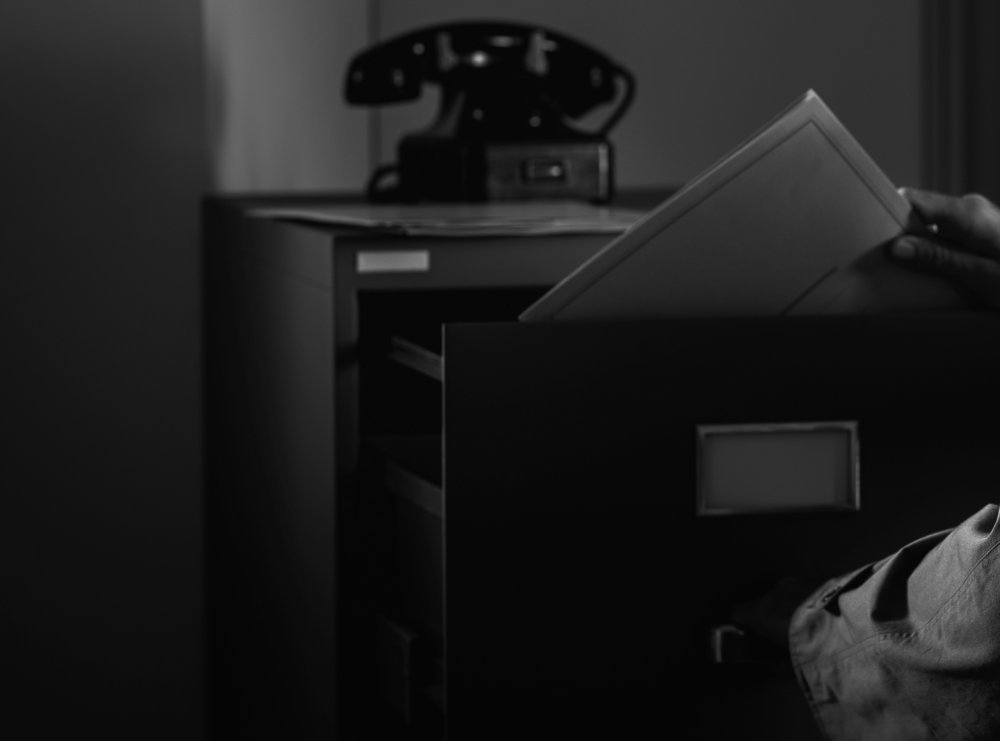 Grayscale Close Up Photo of Vintage spy stealing files in the office