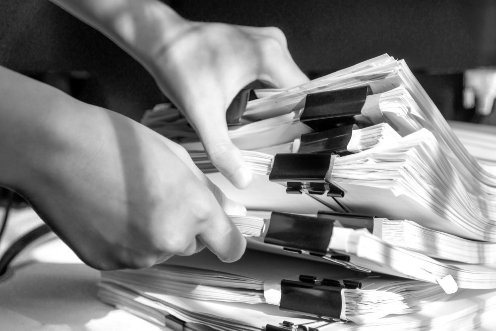 Businesswoman working in stacks of paperwork files for searching infomation