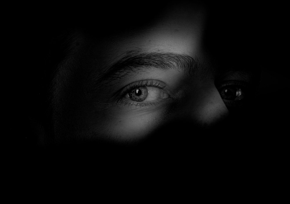 Close Up Photo of eyes in the shadows on Dark Background.